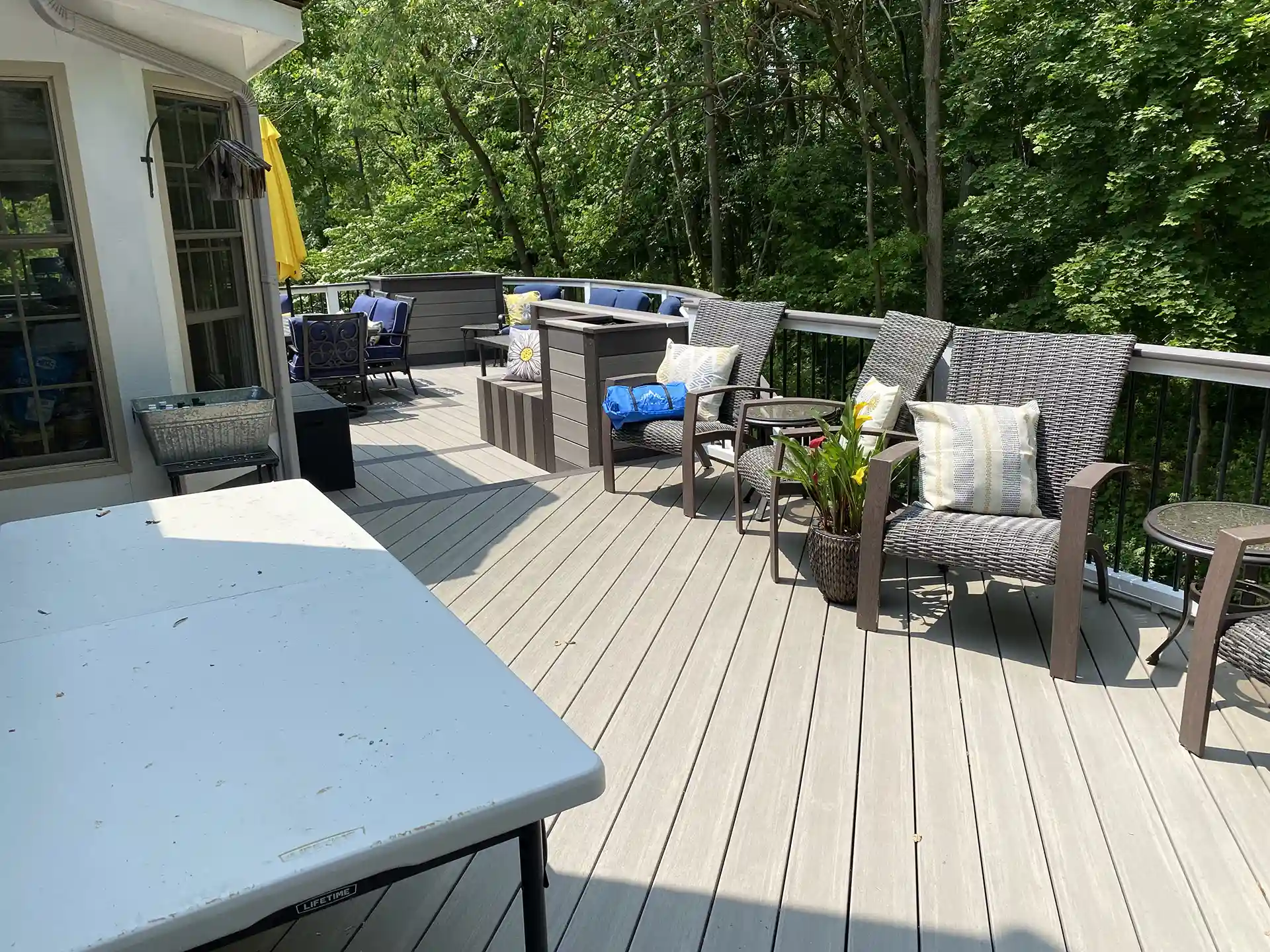 Deck with comfortable seating area, a bar section, and a view of the surrounding trees.