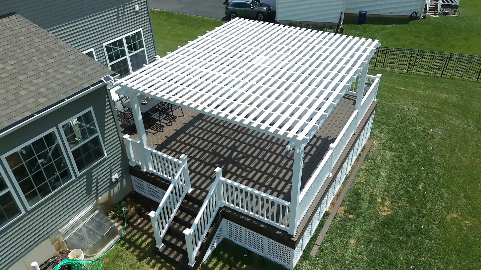 Aerial view of a deck with a white pergola, custom railings, and composite decking, featuring a seamless connection to the backyard.