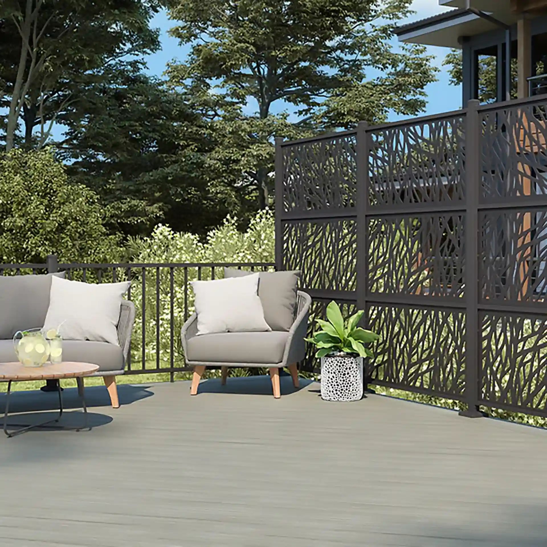 Two light gray 4 Seasons Outdoor SANTANDER Lounge Chairs with white cushions are placed on a gray deck. Next to one of the chairs is a small round table with a glass top. 